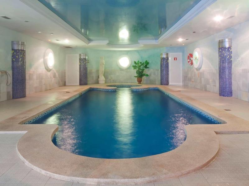 Piscina coperta con acqua blu e colonne decorative in un centro benessere.