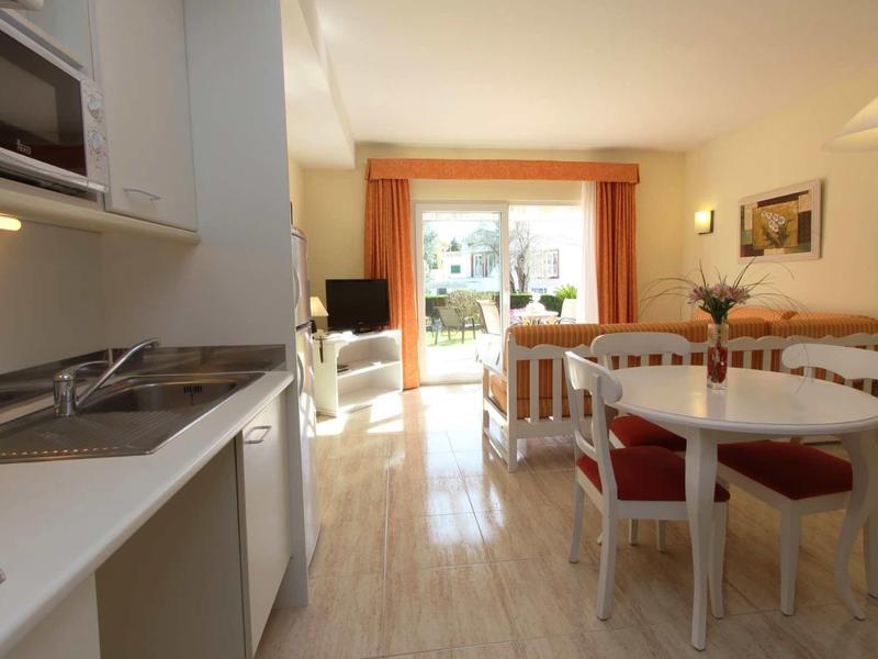 Area cucina e pranzo luminosa con mobili bianchi e vista su terrazza e giardino.