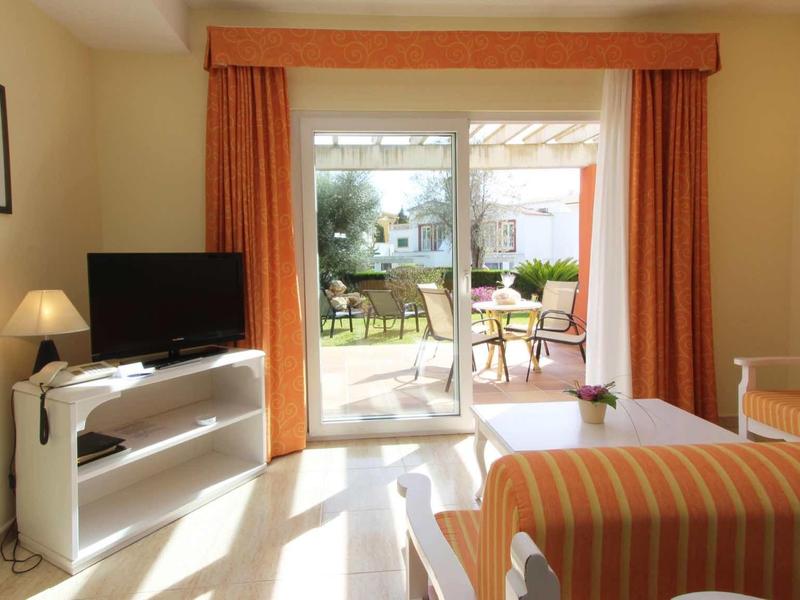 Camera d'hotel luminosa con balcone e vista sul giardino.