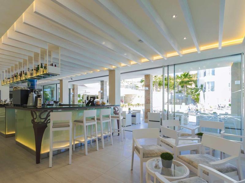 Ristorante luminoso e moderno con mobili bianchi e grandi finestre.