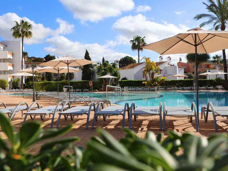 Piscina dell'hotel con lettini e ombrelloni sotto un cielo azzurro