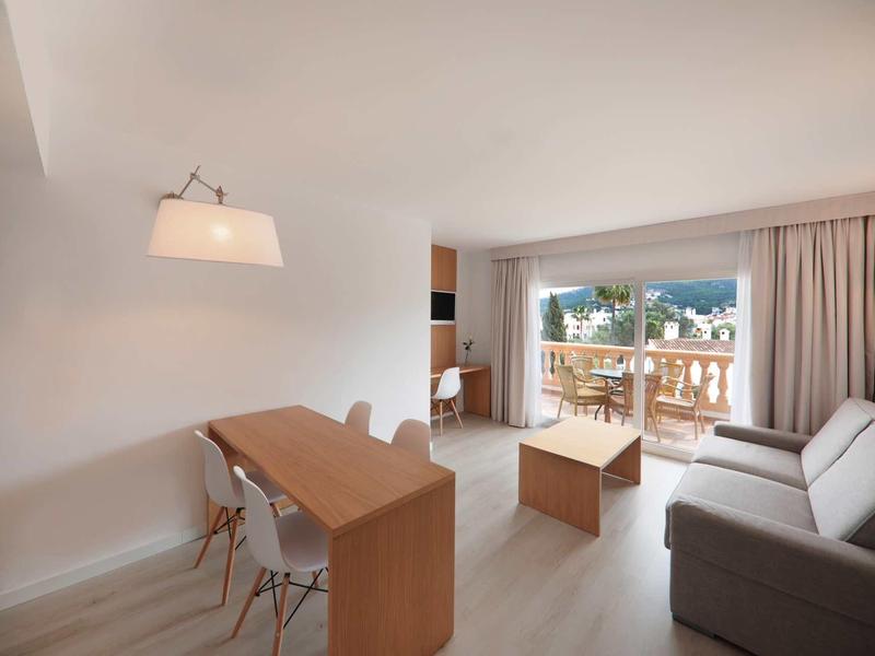 Soggiorno luminoso con tavolo da pranzo, divano e balcone con vista sulle montagne.