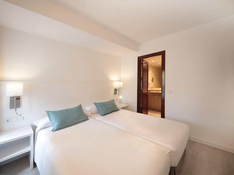 Camera d'hotel moderna con due letti e colori neutri.