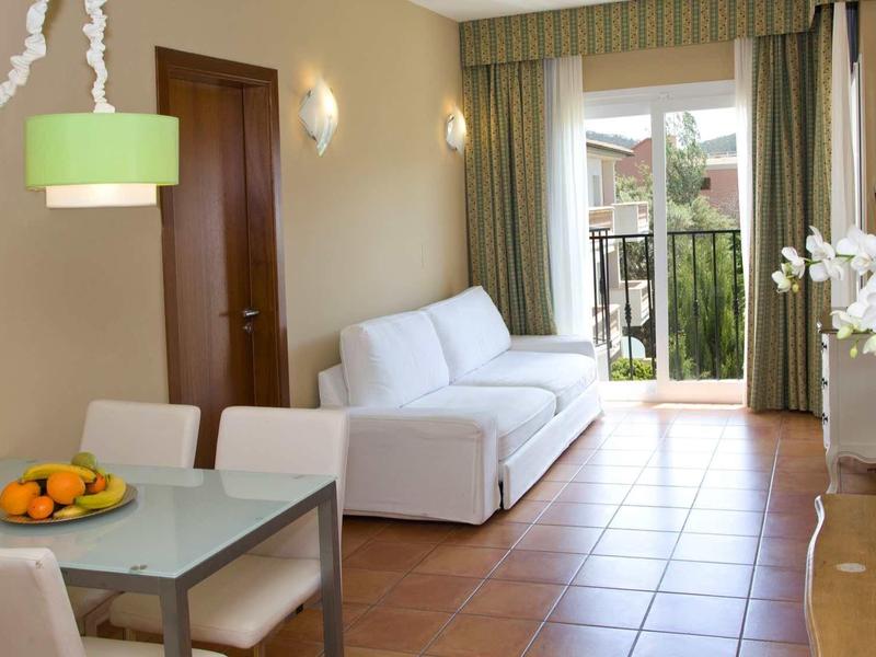 Soggiorno luminoso con tavolo da pranzo, divano bianco e vista sul balcone.