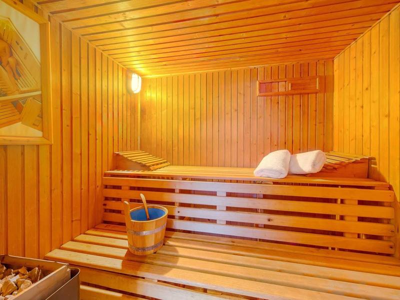 Sauna mit Holzverkleidung, Holzbänken, Aufguss-Eimer und zwei weißen Handtüchern.