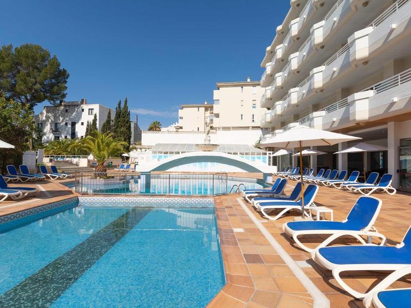 Moderner Hotelpool mit blauen Liegestühlen, großen Sonnenschirmen und weißem Brückenbogen.