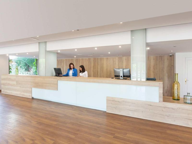 Helle, moderne Rezeption mit Holzvertäfelung und zwei Personen hinter dem Tresen.