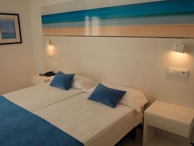 Gezellige hotelkamer met twee eenpersoonsbedden, blauwe decoratie en minimalistisch ontwerp.