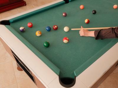 Biljarttafel met gekleurde ballen en een speler die een stoot plant.