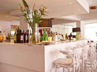 Moderne hotelbar met witte barkrukken en een vaas bloemen op de toonbank