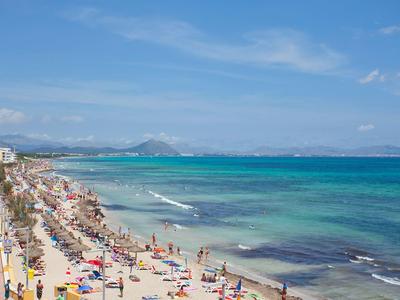 Tłusta piaszczysta plaża z opalającymi się pod niebieskim niebem i czystą niebieską wodą.