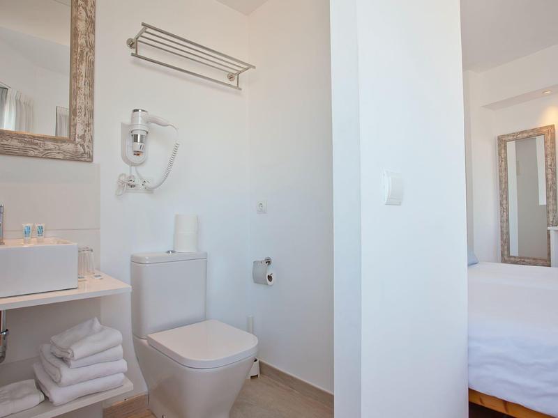 Kompaktowa łazienka z toaletą, umywalką i suszarką obok sypialni z łóżkiem podwójnym.