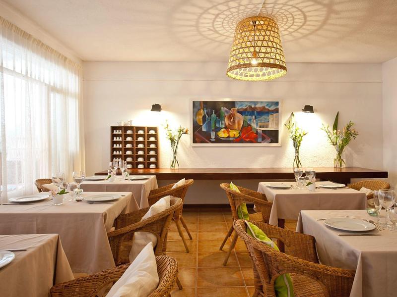 Jasna sala restauracyjna z nakrytymi stolikami, drewnianymi meblami i nowoczesną sztuką ścienną.