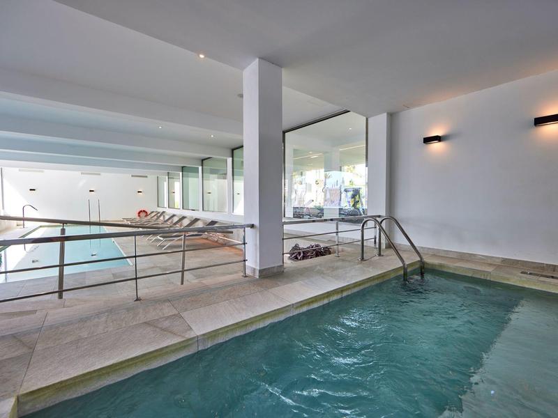 Área interior con dos piscinas, mármol claro y elementos de pared modernos con iluminación.