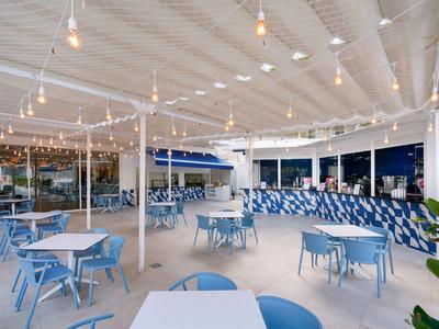 Ristorante all'aperto con sedie blu, tavoli e illuminazione moderna sotto una copertura bianca