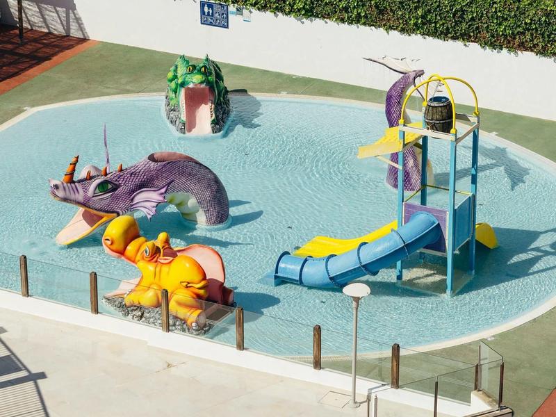 Piscina per bambini con giochi d'acqua a forma di animali e scivoli in un giardino di hotel