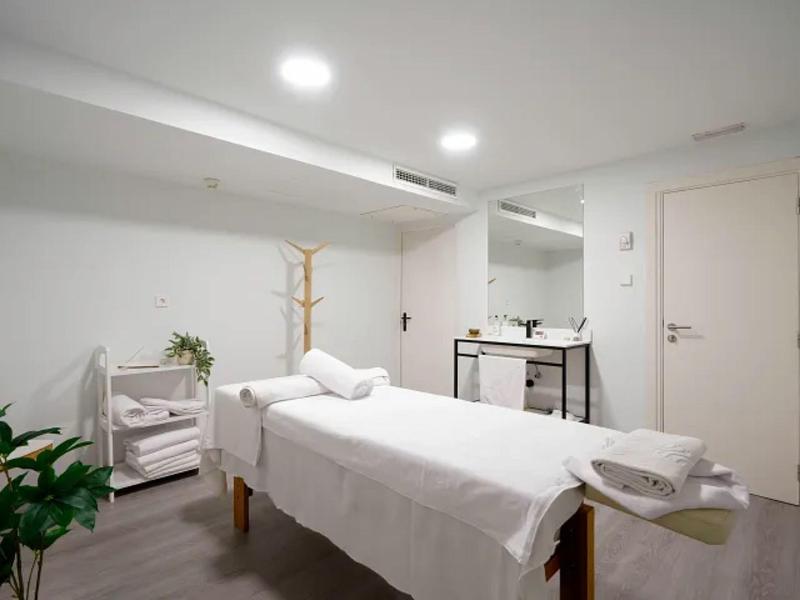 Stanza trattamento luminosa con lettino da massaggio, asciugamani e piante per un'atmosfera rilassante.