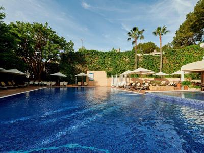 Piscina blu con lettini e palme in un'area alberghiera soleggiata.