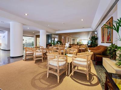 Heller, moderner Hotel-Loungebereich mit Korbmöbeln und Pflanzen.