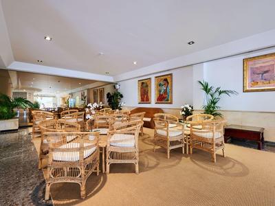 Zona salotto accogliente con mobili in legno e opere d'arte alle pareti dell'hotel.