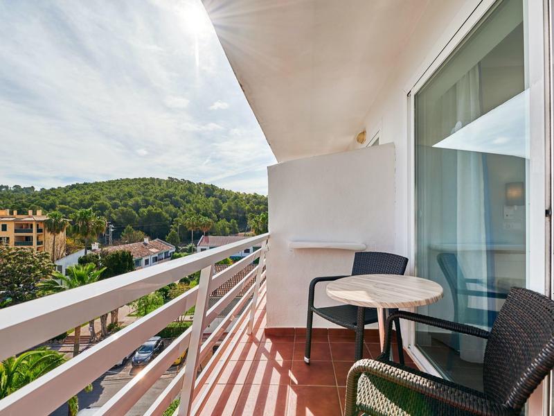 Balcone con tavolo e sedie con vista su colline verdi e edifici.