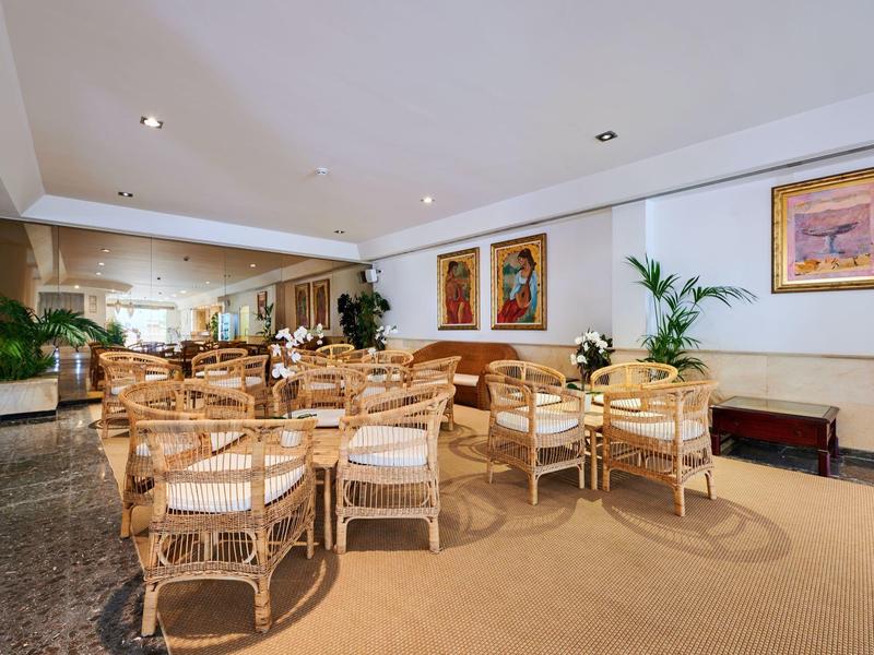 Zona salotto accogliente con mobili in legno e opere d'arte alle pareti dell'hotel.