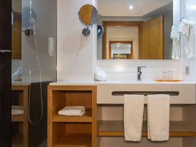 Nowoczesna łazienka z białą umywalką, ręcznikami i lustrem nad drewnianą półką.