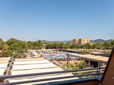 Blick auf Hotelpool und Liegebereiche unter klarem Himmel mit umliegender Landschaft und Bergen.