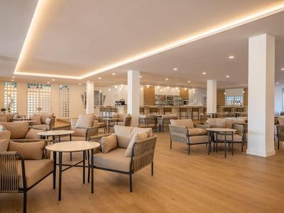 Hell eingerichteter Hotel-Loungebereich mit modernen Sitzgruppen und Holzboden.