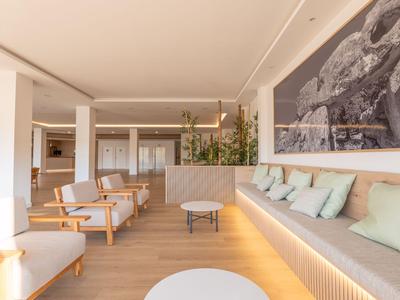 Heller Hotel-Loungebereich mit modernem Holzdesign, Sofas, Sesseln und großer Landschaftskunst an der Wand.