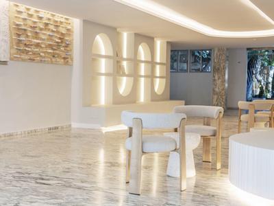 Hall d'hôtel lumineux et moderne avec mobilier blanc et éclairage indirect.