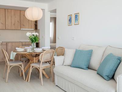 Salle à manger lumineuse avec table en bois, chaises et canapé confortable avec coussins bleus.