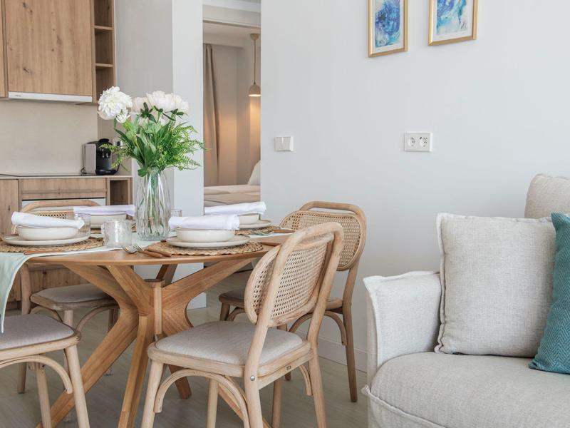 Coin repas moderne avec table en bois, chaises confortables et canapés en arrière-plan.