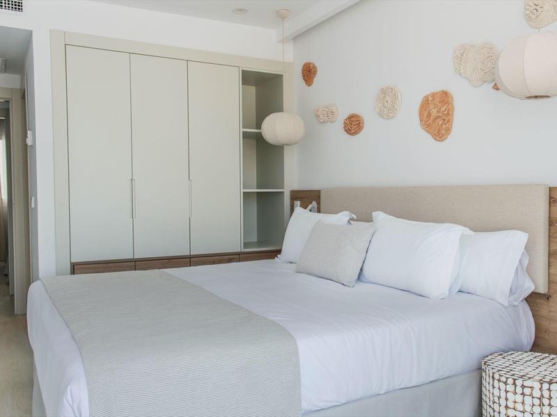 Chambre d'hôtel moderne avec grand lit double, oreillers blancs et éléments décoratifs muraux.