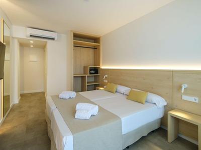 Modernes Hotelzimmer mit Doppelbett, offenem Kleiderschrank und TV an der Wand.