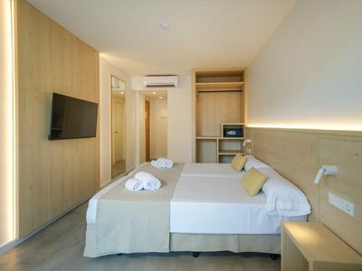 Modernes Hotelzimmer mit Doppelbett, Holz-akzenten und minimalistischer Einrichtung.