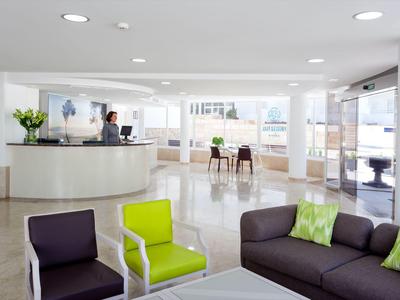 Helle Hotellobby mit modernem Mobiliar und großer Fensterfront.