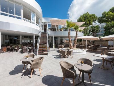 Moderner Außenbereich eines Hotels mit Sitzgelegenheiten und Sonnenschirmen bei Tageslicht.