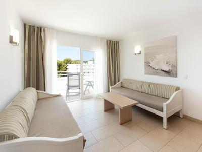 Helles Hotelzimmer mit zwei Sofas, Couchtisch und Balkon mit Blick auf eine Stadt.