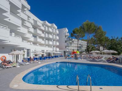 Hotel mit outdoor Pool, Sonnenschirmen und Liegestühlen bei klarem Himmel.