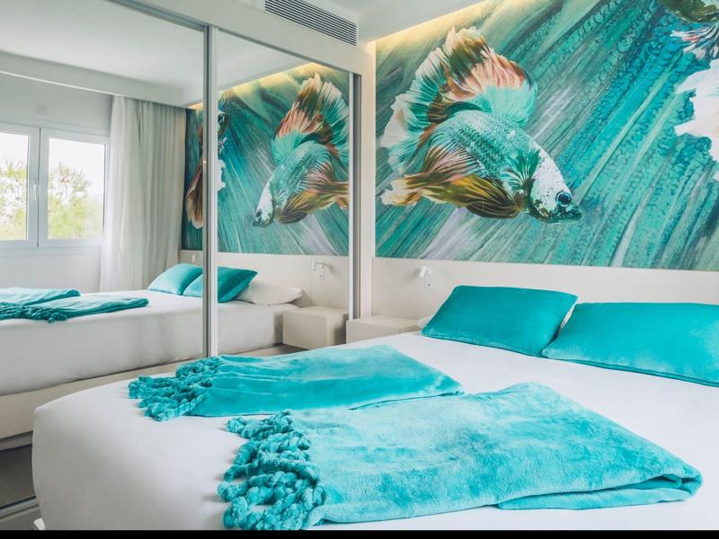 Modern slaapkamer met zeemeerminnenmuur en turquoise beddengoed in een hotelkamer.