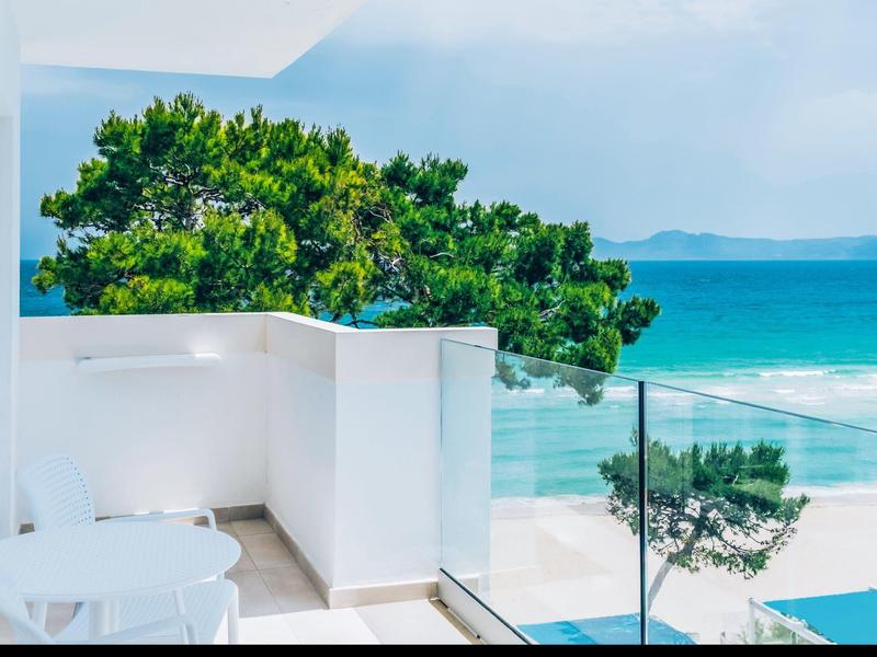 Terras met glazen railing met uitzicht op het strand en de turquoise zee.
