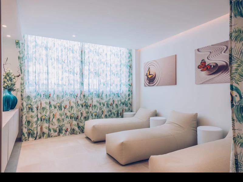 Moderne kamer met lichte meubels en patroon gordijnen bij grote ramen.