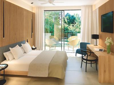 Modern hotelkamer met groot bed, houten meubels en uitzicht op terras.