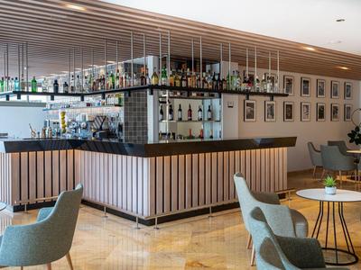 Nowoczesny bar hotelowy z drewnianym kontuarem, półkami i wygodnymi fotelami