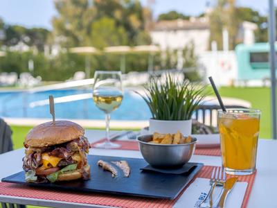 Burger, frytki i napoje na stole obok basenu hotelowego.