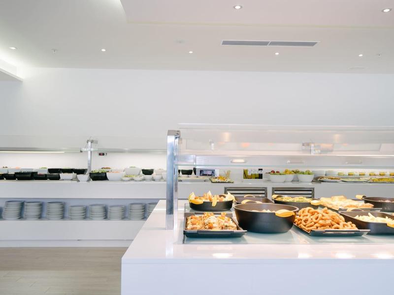 Nowoczesny bufet z wyborem wypieków i pieczywa w jasnej restauracji hotelowej.