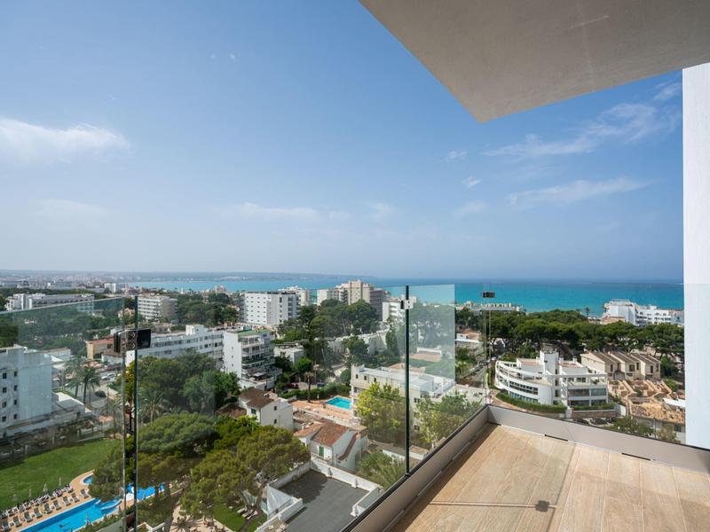 Balkon z przeszklonym balustradą z widokiem na miasto i morze przy czystym niebie.