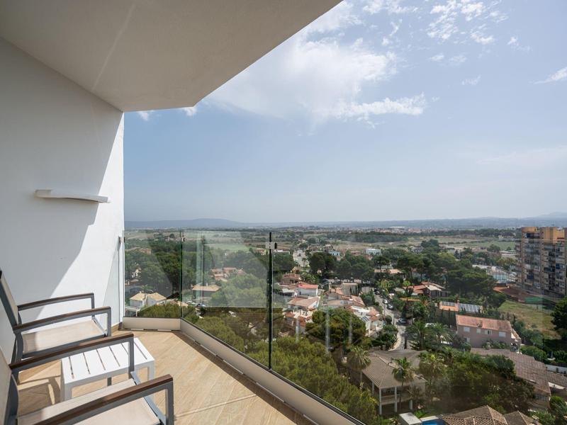 Balkon z dwoma krzesłami z widokiem na miejskie krajobrazy pod pochmurnym niebem.