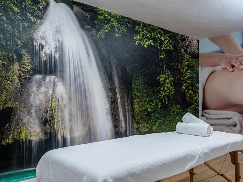 Pokój zabiegowy z łóżkiem do masażu przed dekoracją ściany z wodospadem w spa.